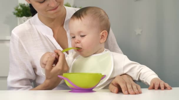 Ребенок с миской и ложкой пробует есть — стоковое видео