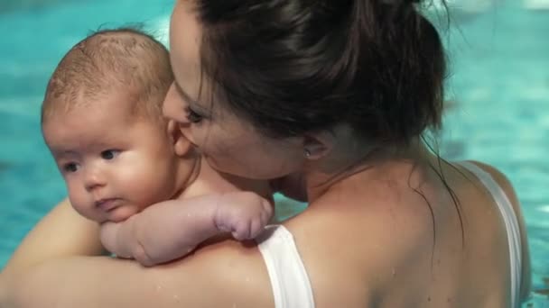 Мати цілує дитину в басейні — стокове відео