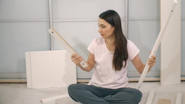 Verwirrte Frau baut Möbel zusammen — Stockvideo