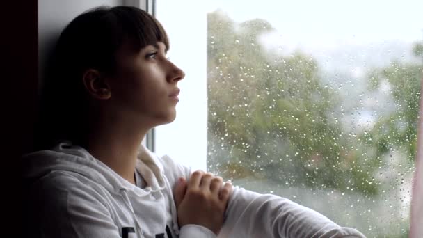 Депрессивная молодая женщина у окна дома — стоковое видео