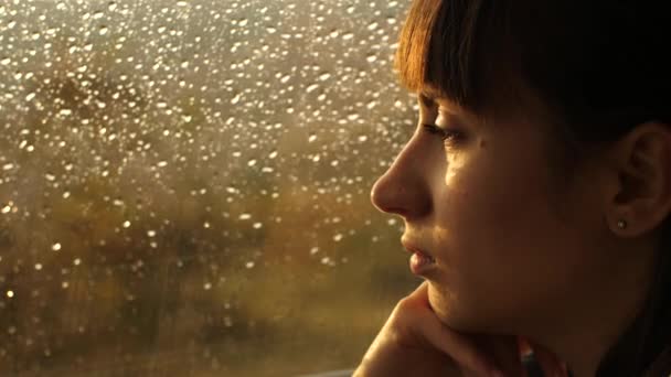 Woman sitting alone close to window with rain drops — ストック動画