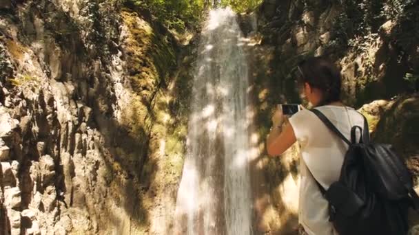 Mujer tomar una foto de la cascada — Vídeo de stock