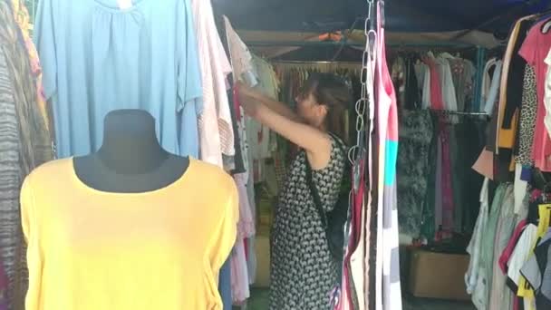 Mujer eligiendo ropa en el mercado — Vídeos de Stock