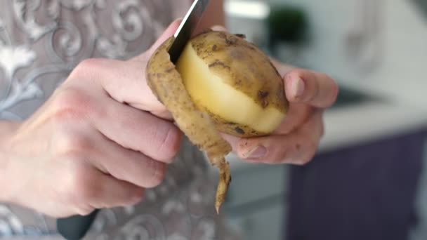 Händer peeling potatis i köket — Stockvideo