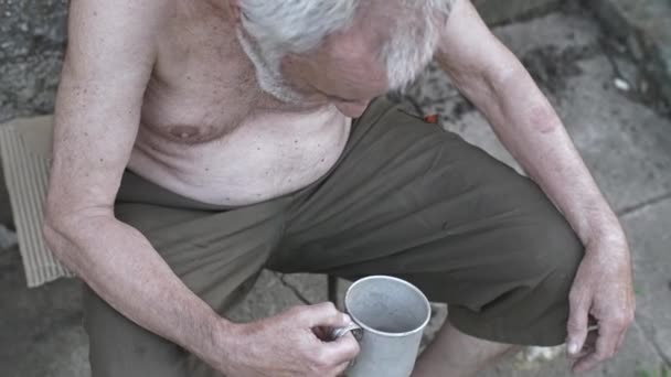 Dakloze man met een kopje vragen om donatie — Stockvideo