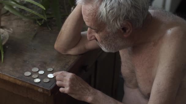 Gammal man räkna mynt på ett bord — Stockvideo