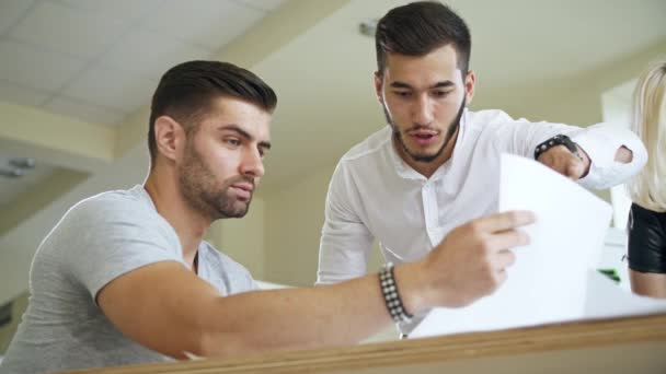 Два чоловіки в офісі дивляться на документи — стокове відео