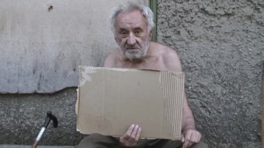 Dilenci boş bir tabela ile sokakta oturuyor