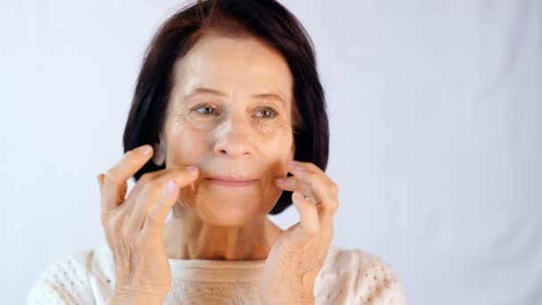 Mujer adulta aplicando crema en la cara — Vídeo de stock