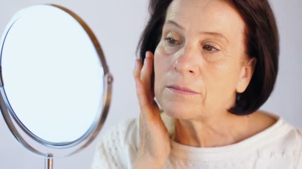 Femme âgée regardant la peau sur le visage — Video