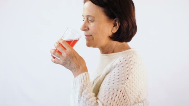 Mujer bebiendo jugo rojo sobre fondo blanco — Vídeos de Stock