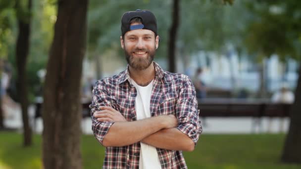 Glimlachende man in een hemd en pet met gevouwen armen — Stockvideo