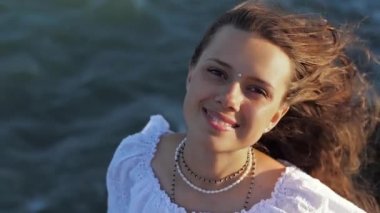 Deniz kenarında rüzgarda savrulan bir kadının portresi.