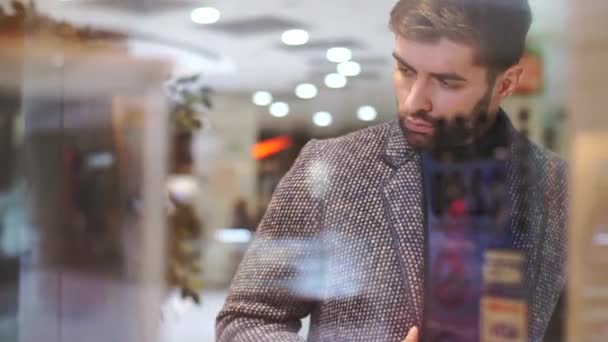 Man looks at a shop window with clothes — Stock Video