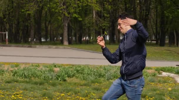 Zwariowany człowiek biegnie przez łąkę z kwiatem. — Wideo stockowe
