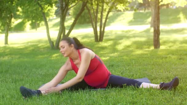 Mujer embarazada estirándose sobre la naturaleza — Vídeos de Stock