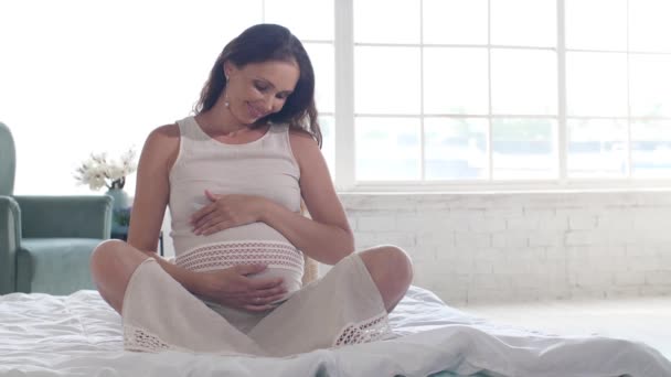 Donna incinta su un letto accarezza la pancia — Video Stock