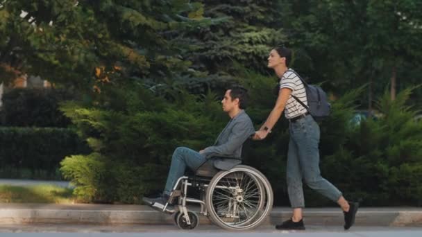 坐在轮椅上的男人和他的妻子在户外 — 图库视频影像