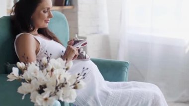 Doğmamış bebek için ayakkabıyla oynayan kadın.