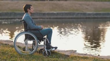 Gölün kenarında tekerlekli sandalyede bir adam var.