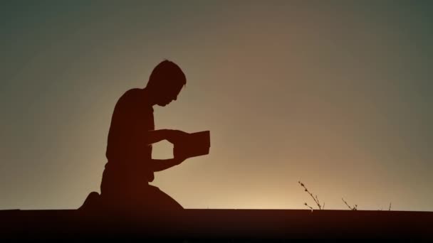 Uomo che legge libro religioso la sera — Video Stock