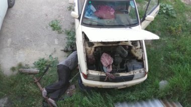 Kırsal adam eski arabayı tamir ediyor.