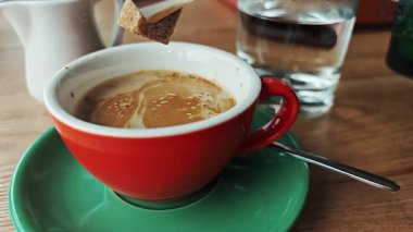 A chunk of natural cane sugar drops into a steaming cup of coffee.