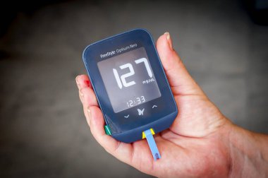 Onun elinde tutan bir Freestyle Optium Neo şeker ölçüm yüksek glikoz düzeyi sonuçlarla test kan sonra gebelik şeker hastalığı olan kadın hasta. Gebelik diyabet stok görüntü.