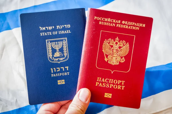Hand holding two foreign passports: the passport of State of Israel and the passport Russia (Russian Federation), dual citizenship concept illustration.