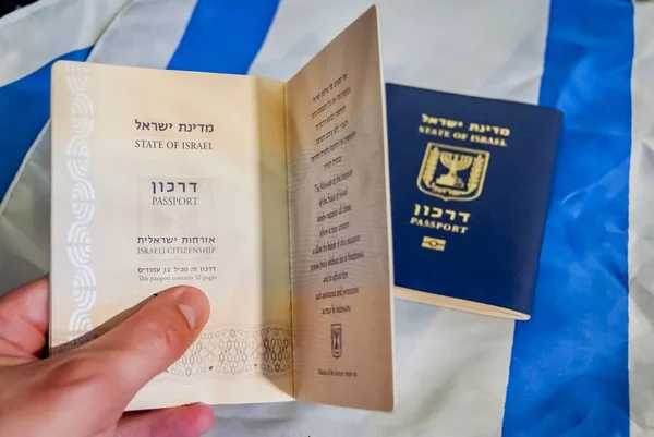イスラエルの国旗を背景にイスラエルのパスポートを持っている手 イスラエルの市民権概念 イスラエル ダーク パスポート イメージ — ストック写真