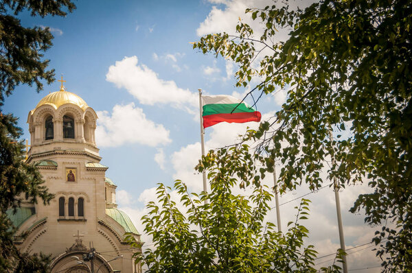 SOFIA, BULGARIA. August 4, 2018. Bulgarian flag in the sky with a Alexander Nevsky Cathedral golden dome on the background. The St. Alexander Nevsky Cathedral is a Bulgarian Orthodox cathedral in Sofia, the capital of Bulgaria. Sofia concept image