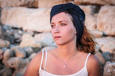 Güzel beyaz genç bir kadın ile taş duvar arkasında batımını başında siyah bir şal ile. Yüzünde günbatımı renkleri.