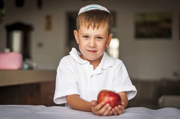 Beyaz mavi gözlü yakışıklı bir geleneksel Yahudi beyaz Kipa şapkalı bir elma onun elinde. Rus Yahudi çocuk Yahudi yeni yılı - Rosh Hashanah kutluyor.