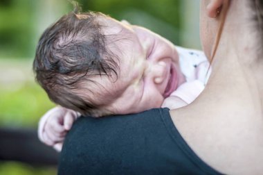 Tatlı aç yeni doğan bebek kız umutsuzca annesi omzunda ağlıyor. Mide krampları, Bebek kolik tedavi, Bebek yakınmalar ağrı, rahatsızlık bebek bağırsak gaz belirtileri.