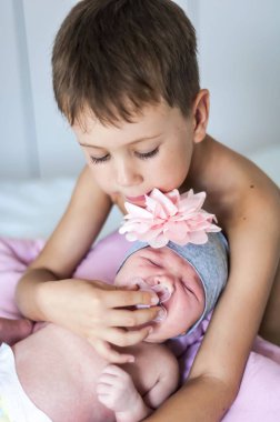 Sevimli beyaz okul öncesi yaş 6 yaşındaki bir çocuğa yeni doğan bebek kardeşi ağlayarak rahatlatıcı. Ona onu sakinleştirmeye bebek kukla emzik meme verir. Sevgi dolu büyük kardeşi kavramı görüntü.