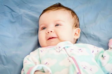 Sevimli gülümseyen beyaz bebek mutlu bir şekilde bakım annesine bakıyor. Mutlu çocukluk kavramı görüntü.