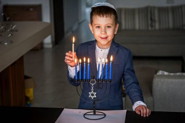 Sevimli beyaz Yahudi çocuk ışık mumlar bir geleneksel Hanukkah menorah Pyres, Yahudi Bayramı Hanuka kavramı üzerinde.