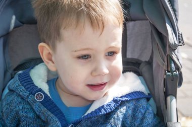 Sevimli sarışın beyaz üç yaşındaki çocuk dışında bir bebek arabası bebek arabası.