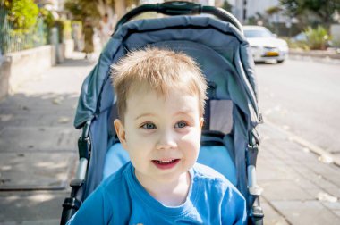 Sevimli sarışın beyaz üç yaşındaki çocuk dışında bir bebek arabası bebek arabası.