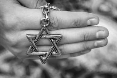 Geleneksel Yahudi sembolü David Yıldızı ile anahtarlık tutan genç bir kadının eli. Uluslararası Holokost anma günü, Holokost anıtı için bir konsept imge. Siyah beyaz görüntü.