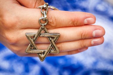 Geleneksel Yahudi sembolü David Yıldızı ile anahtarlık tutan genç bir kadının eli. Uluslararası Holokost anma günü için bir konsept imge, Holokost anıtı.