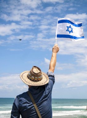 Tel Aviv, İsrail. 9 Mayıs 2019. İsrailli Kafkas adam mavi gökyüzünde askeri uçaklarda bayrak sallayarak ve 71 İsrail Bağımsızlık Günü kavramı havacılık gösterisi izliyor.