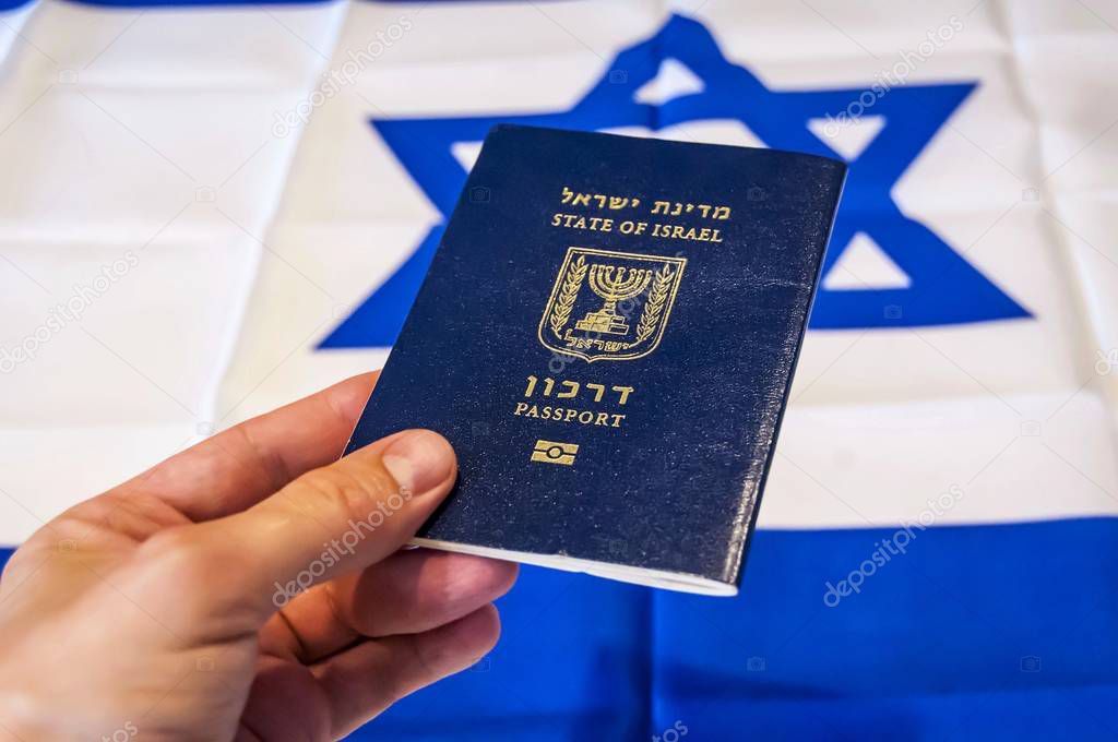 Hand holding the passport of the State of Israel, Israeli flag on the background. Israel citizenship concept, Israeli biometric 
