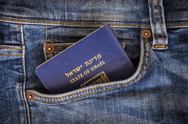 A blue passport of the State of Israel sticking from a pocket of blue denim jeans. Israeli tourist travel, Israel citizenship concept, Israeli biometric (darkon) passport illustrative image. See the world