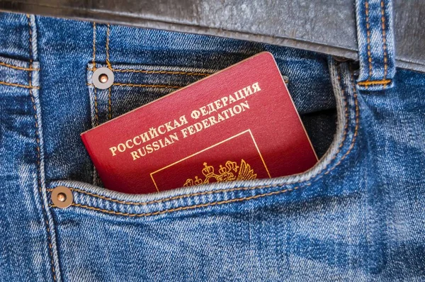 A red passport of Russia sticking from a pocket of blue denim jeans. Russian passport, Russian tourist travel concept image.