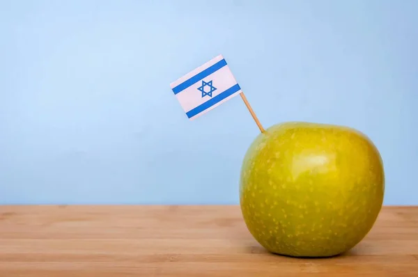 Granny Smith green apple grown in Israel with a little Israeli flag. Fruit made in Israel, Israeli fruits concept image. Jewish New Year Rosh Hashana illustration.