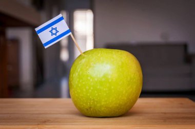Ahşap bir masa üzerinde İsrail küçük bir bayrak ile Yeşil Granny Smith elma. Yahudi Yeni Yıl Rosh Hashana veya Made in Israel, anti Bds hareketi, İsrail tarım meyvesi ürünü için bir kavram görüntüsü.