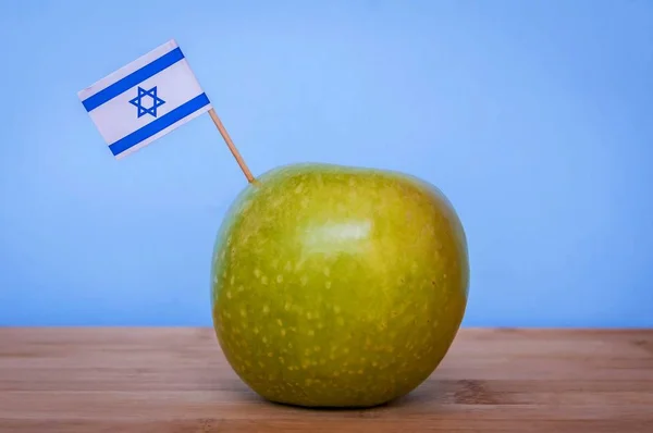 Granny Smith green apple grown in Israel with a little Israeli flag. Fruit made in Israel, Israeli fruits concept image. Jewish New Year Rosh Hashana illustration.