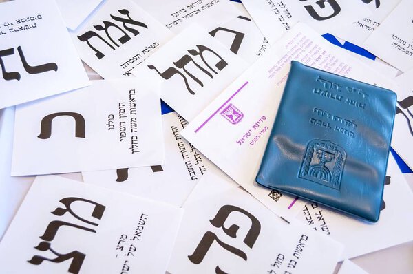 JERUSALEM, ISRAEL. July 5, 2019. Israeli national ID in a blue plastic case over various ballot papers of different Israeli political parties. Text in Hebrew. Israel Parliamentary Elections. Knesset