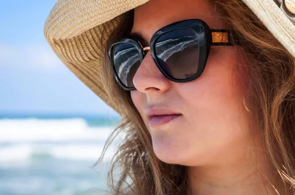 Onu arka planda deniz dalgaları ile deniz kenarında sıcak bir yaz gününde güneş gözlüğü ile bir saman şapka onu geç 20s mutlu güzel genç Kafkas Rus kadın. Deniz konsepti görüntüsünde yaz tatili, mutluluk fikri. Mutlu 30 yaşında yaşlılık